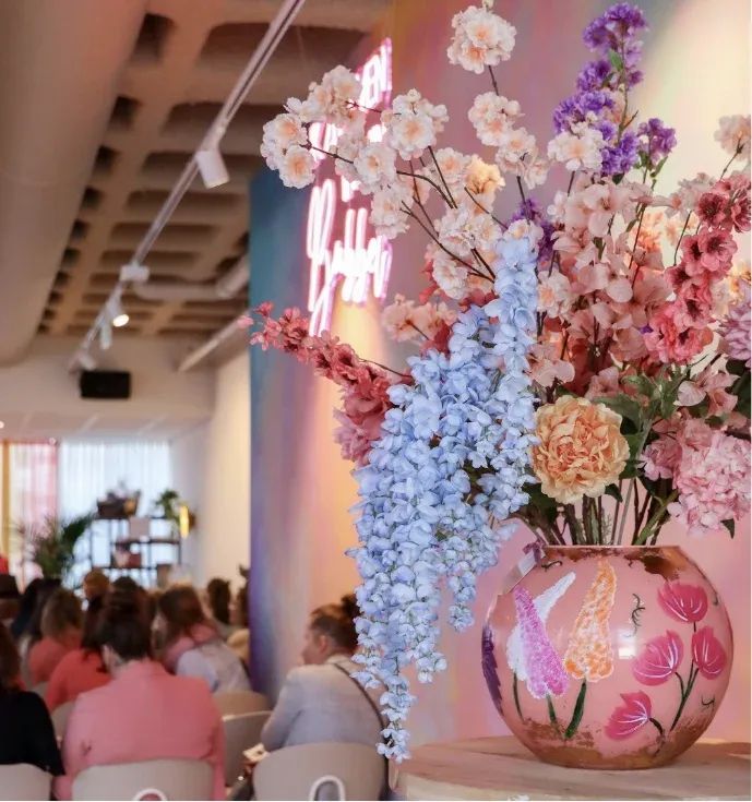 Een levendig bloemstuk met roze, paarse en blauwe bloemen siert een evenementenruimte.