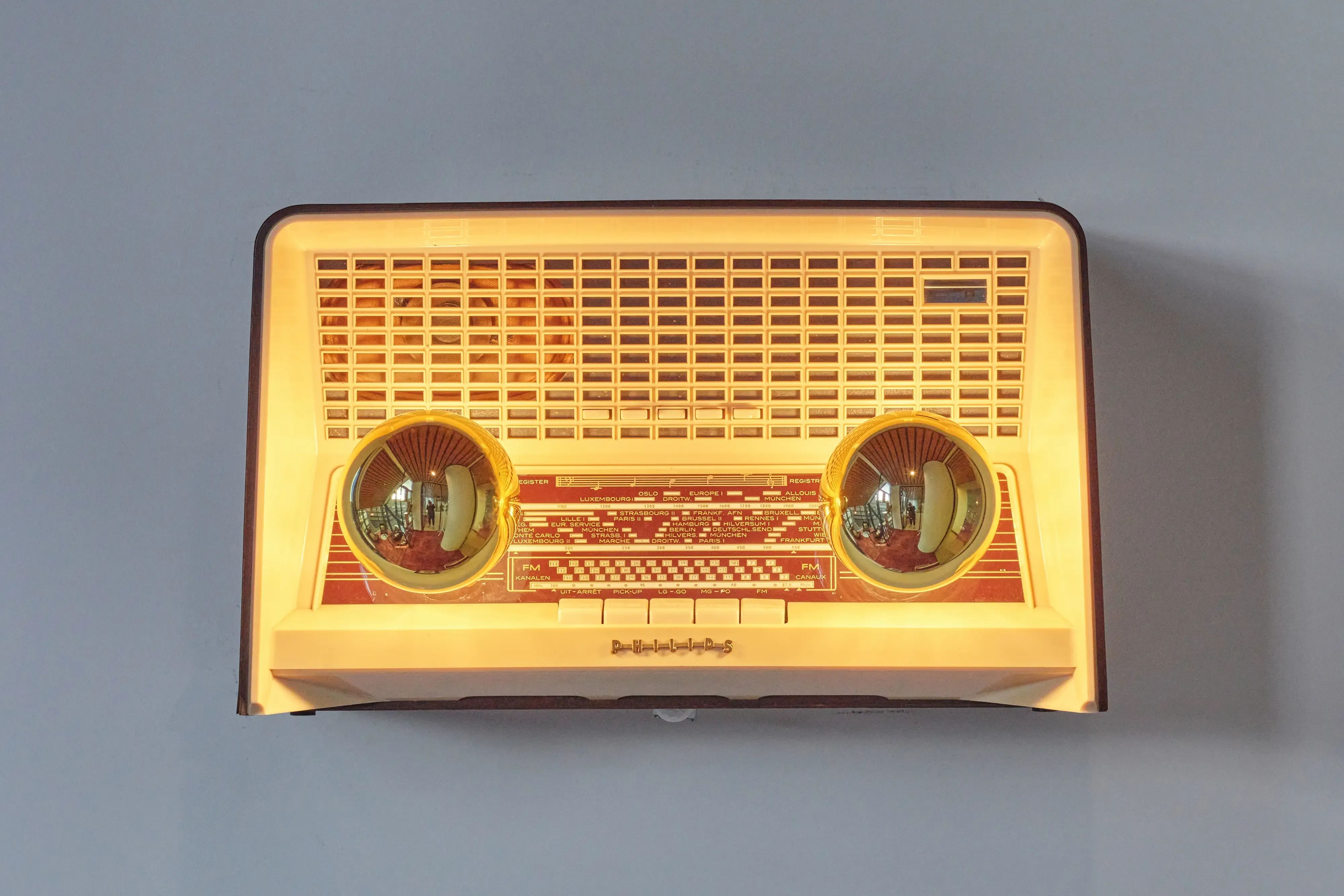 Een vintage, gloeiende radio met een lichtgekleurd rooster en twee opvallende ronde afstemknoppen.