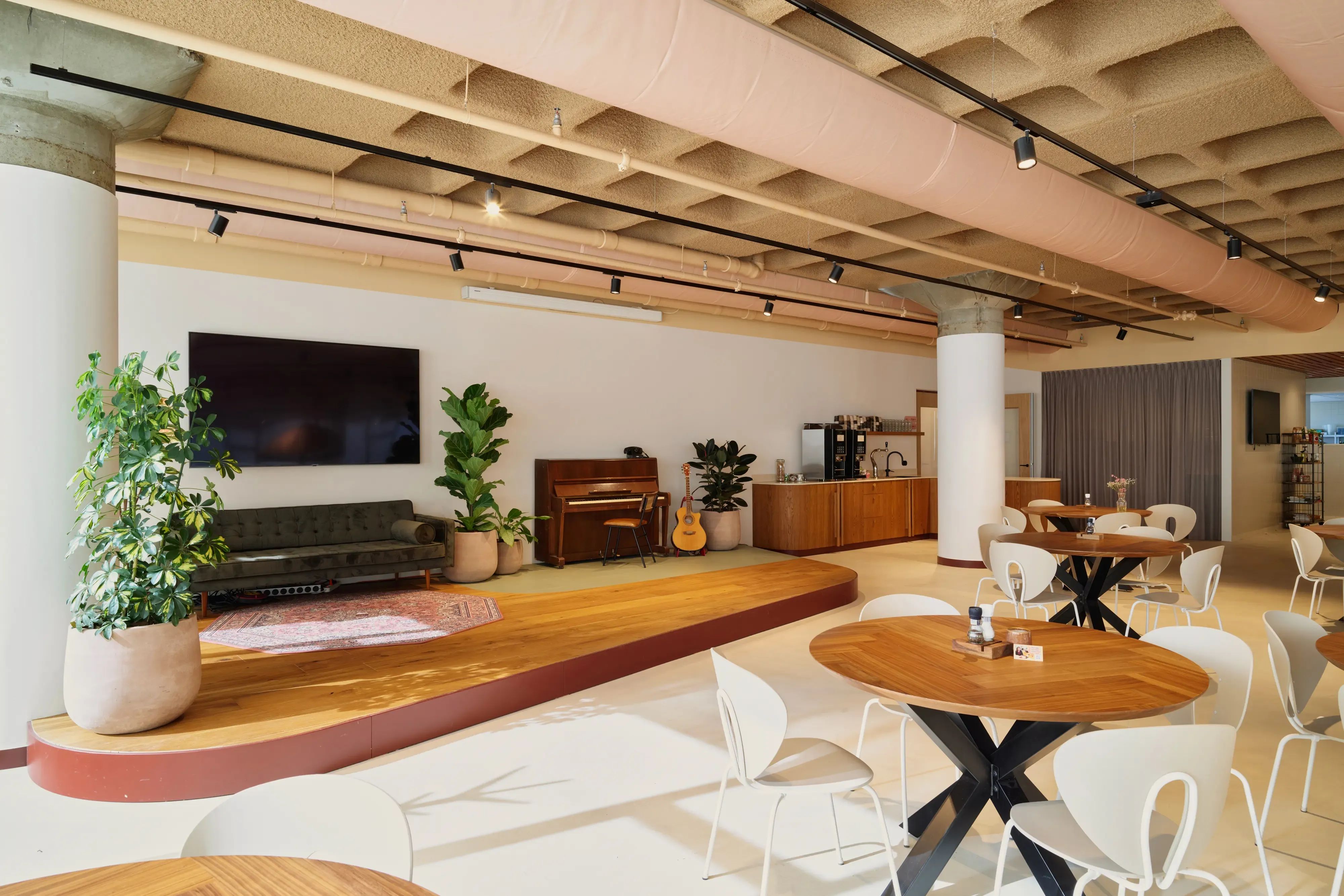 Een moderne, open lounge met een podium, koffiebar en zitjes.