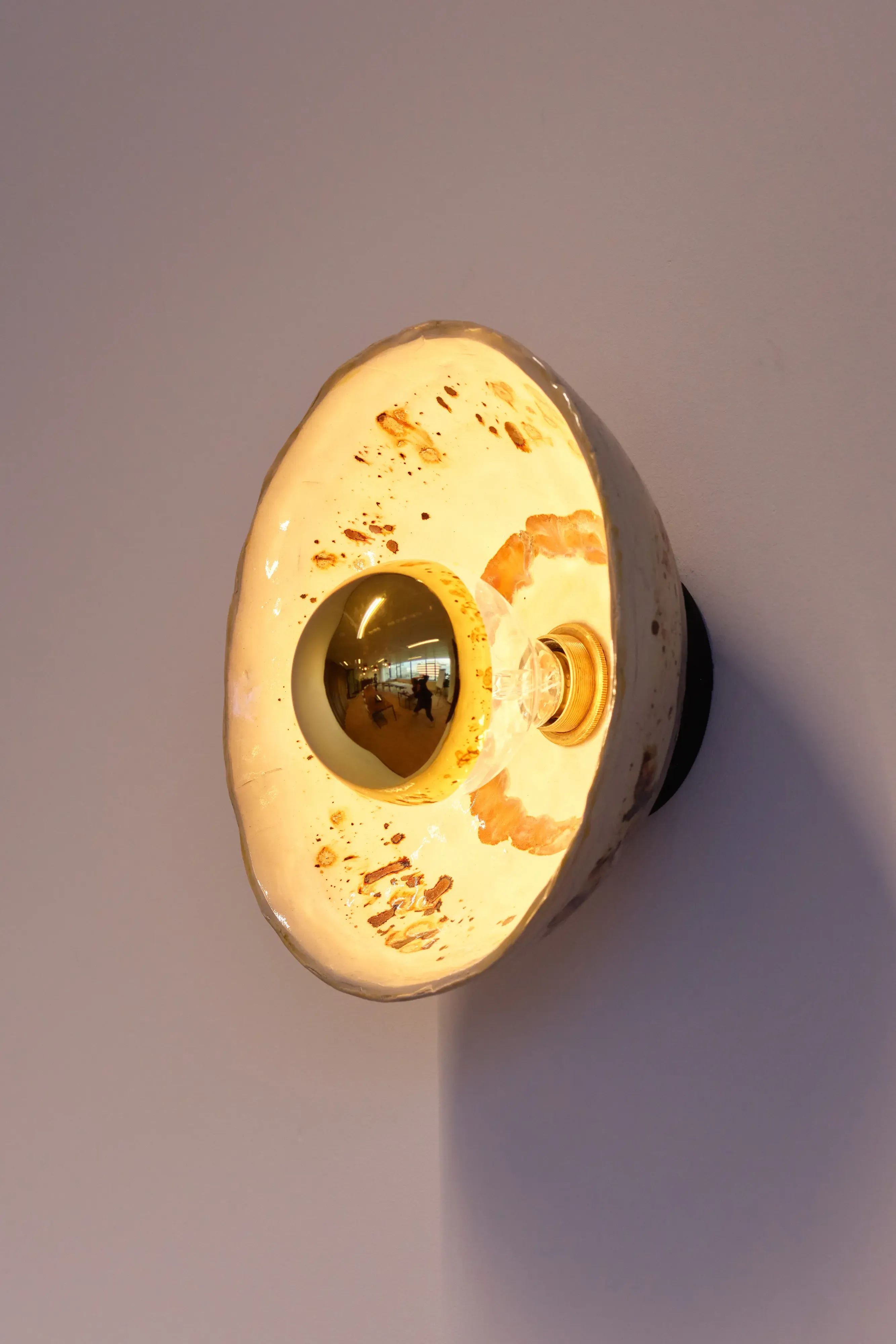 Geel wandlampje bevestigd aan witte muur in moderne, sfeervolle interieuromgeving met warme verlichting.