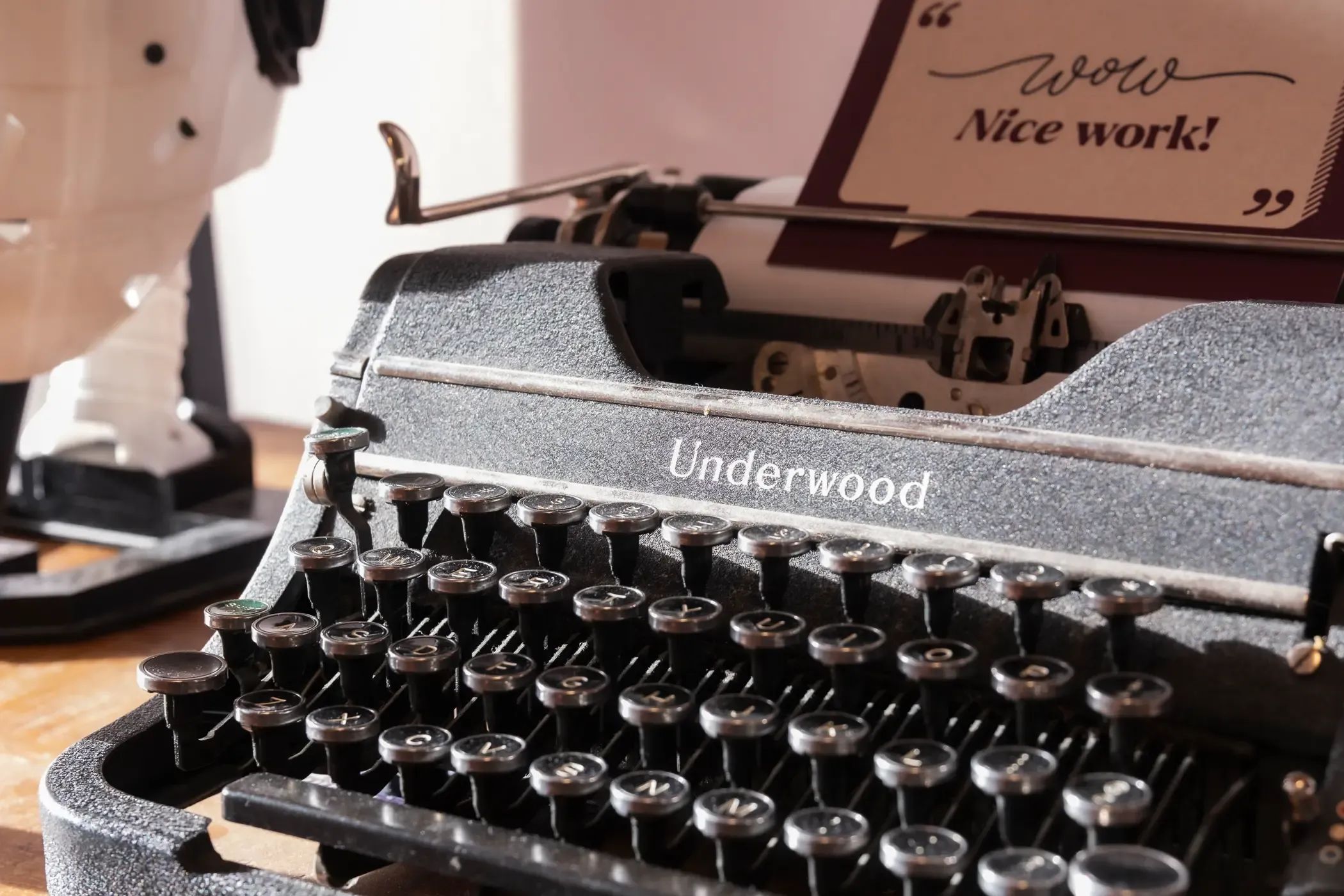 Een vintage typemachine met een kaart met daarop "Nice Work!"
