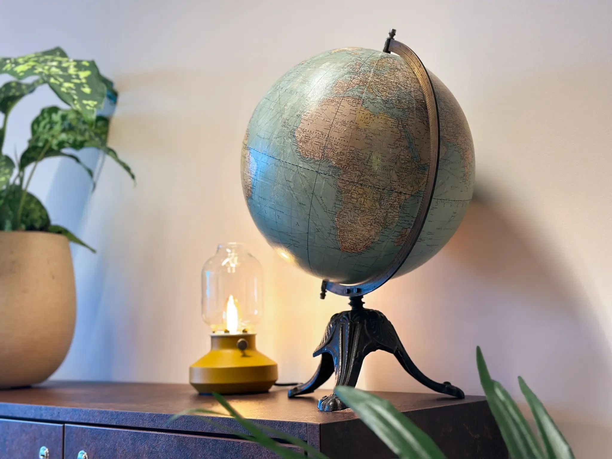 Aardebol naast een brandend lampje op een houten kastje 