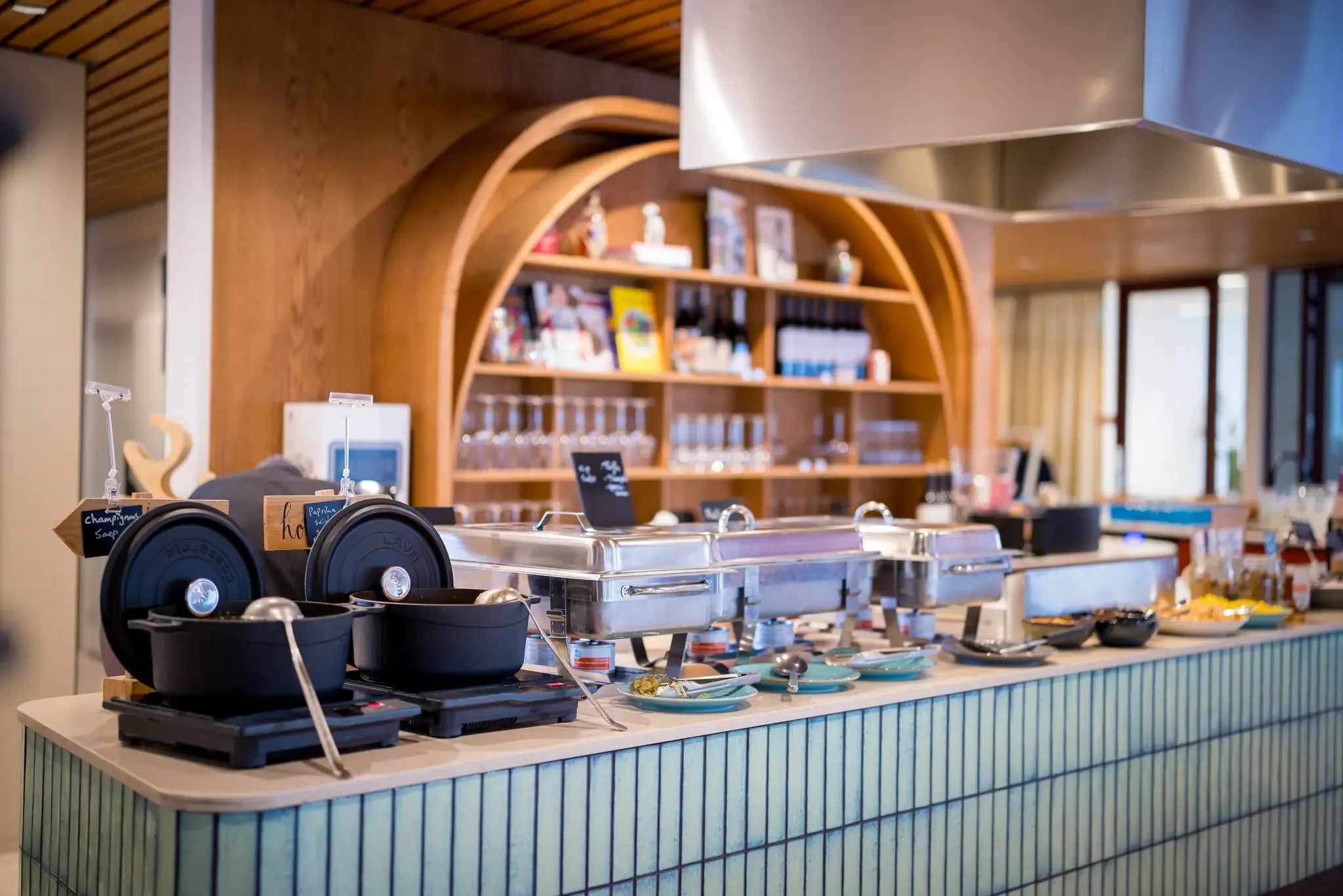 Een moderne buffetlijn met diverse warme en koude gerechten op een stijlvolle betegelde toonbank.